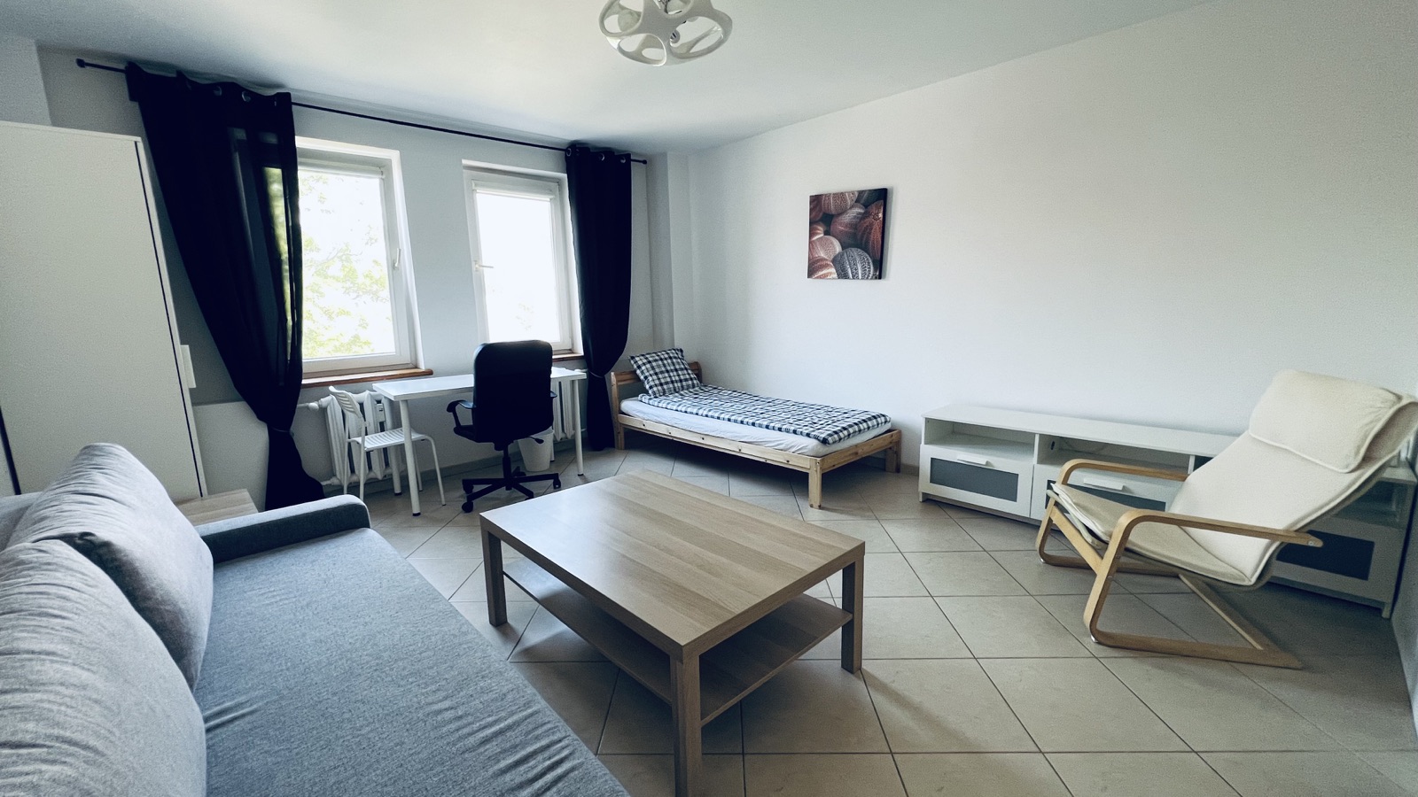 Bright private room with a bed, desk and sofa